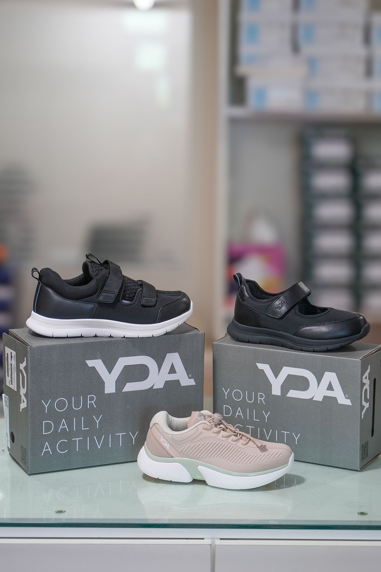 Tre paia di scarpe per bambini YDA su scatole grigie con la scritta