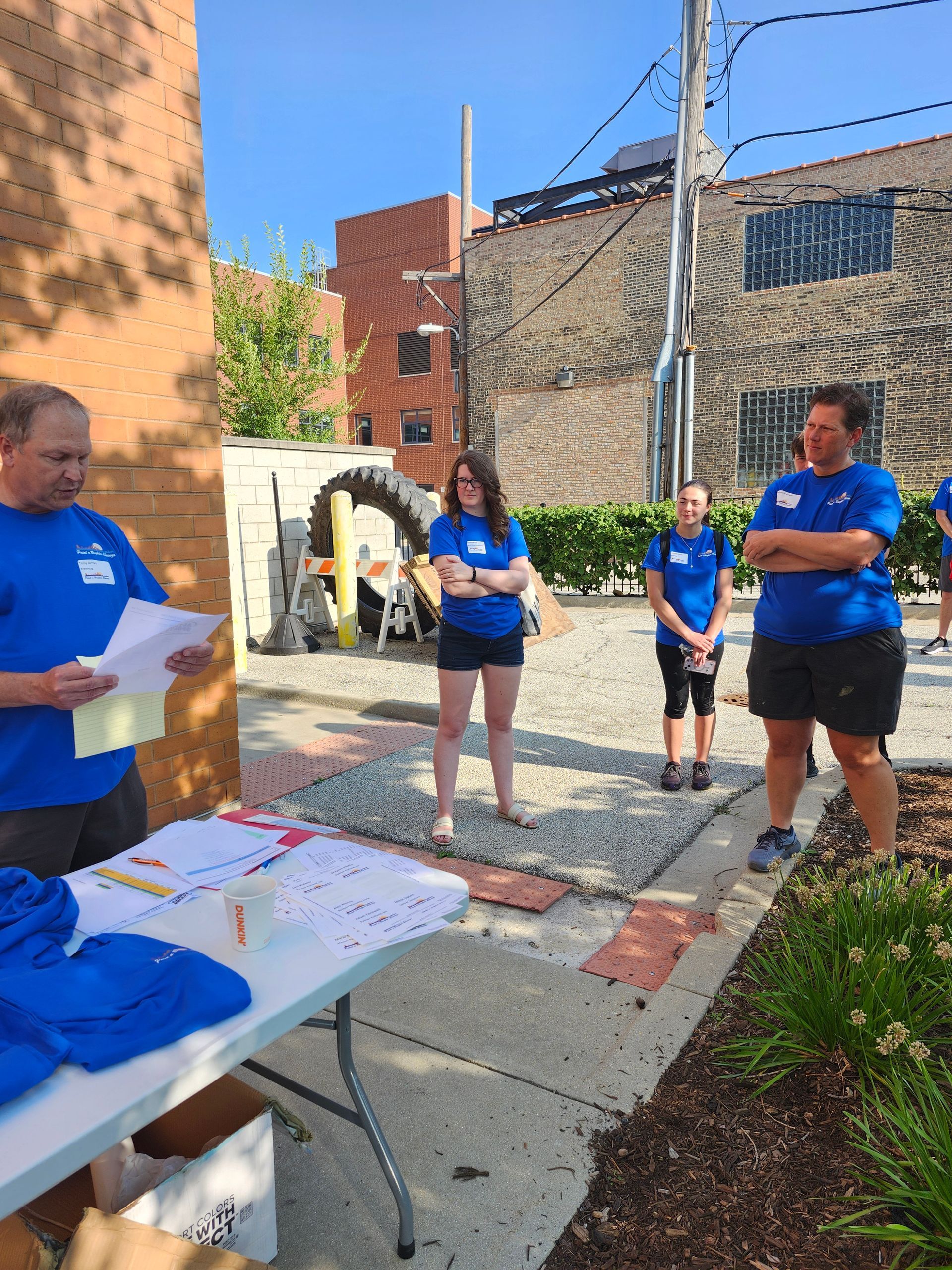A group of people in blue shirts are standing around a table