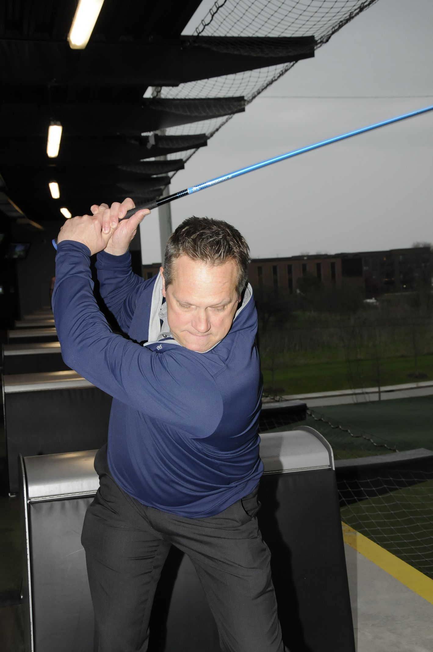 A man is swinging a golf club on a driving range.