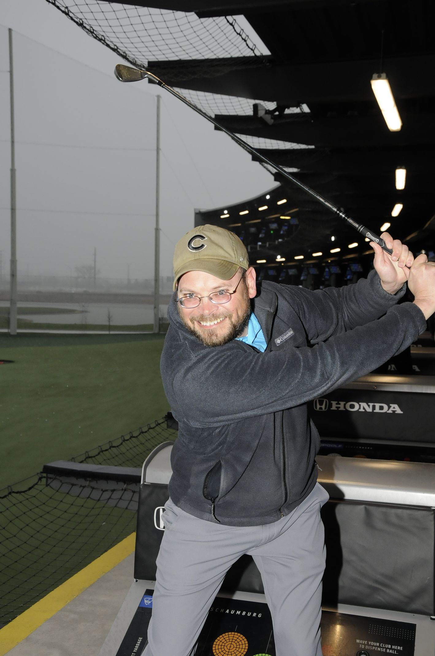 A man is swinging a golf club at a honda car