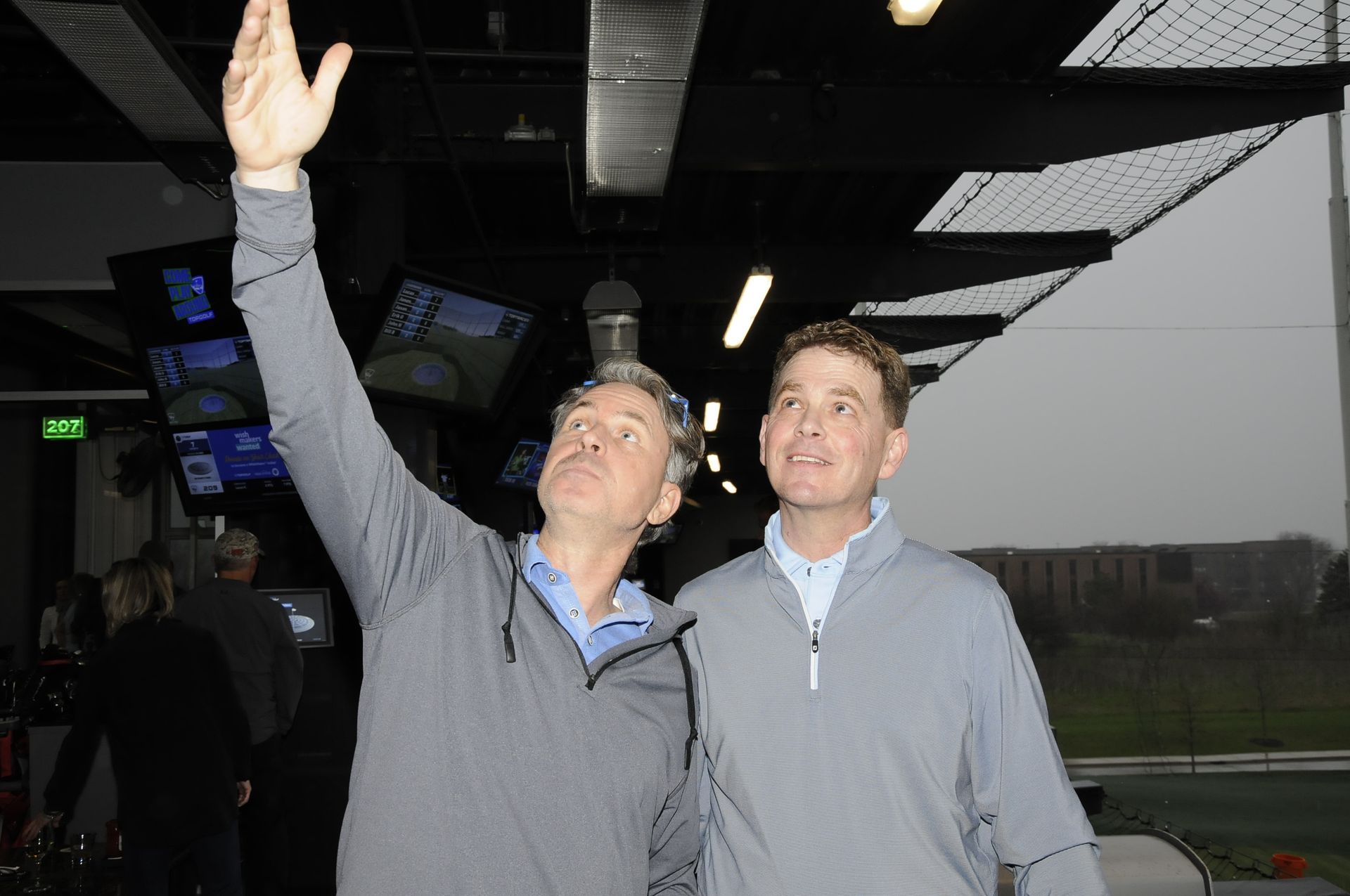Two men are standing next to each other and looking up at something.