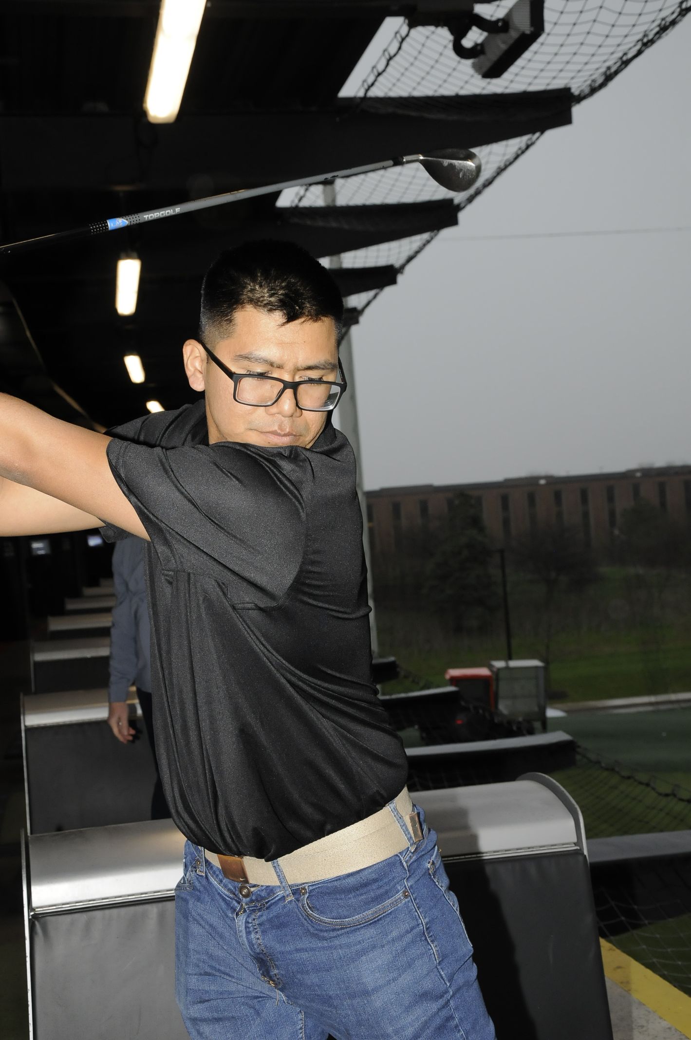 A man wearing glasses is swinging a golf club