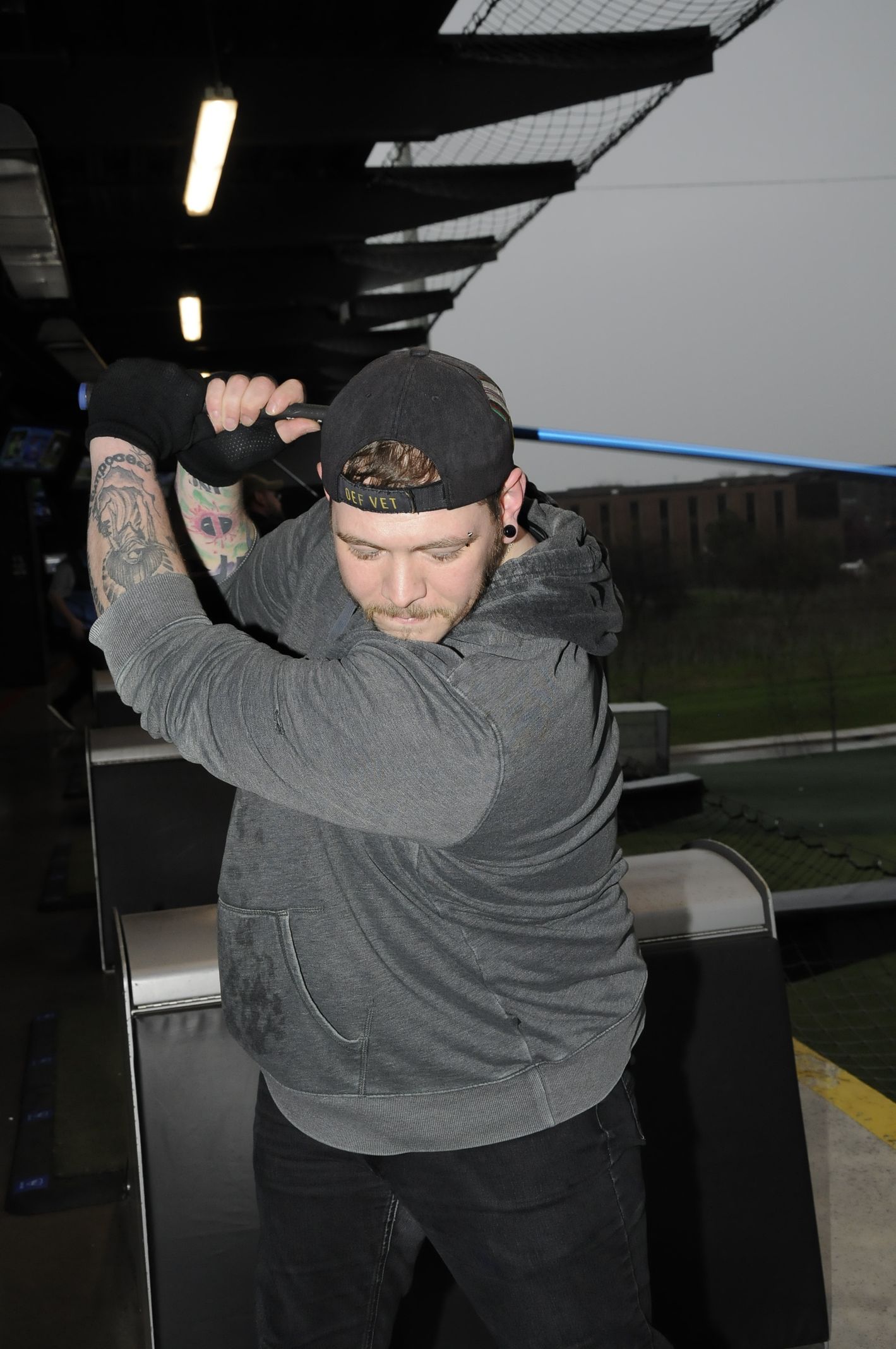 A man with a tattoo on his arm is swinging a golf club