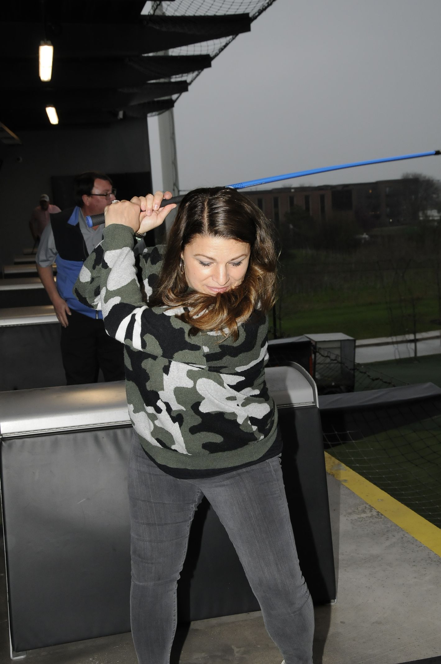 A woman is swinging a golf club on a golf course.