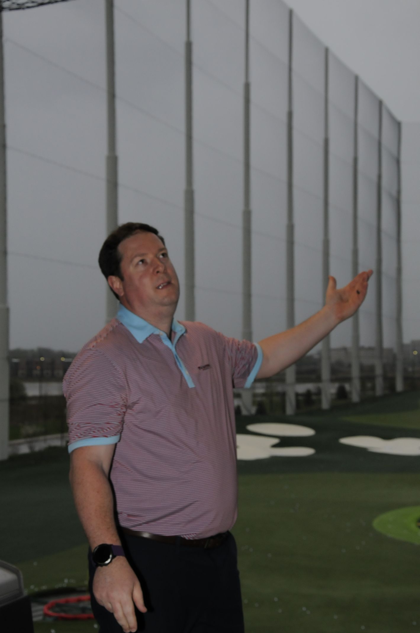 A man in a purple shirt is standing on a golf course