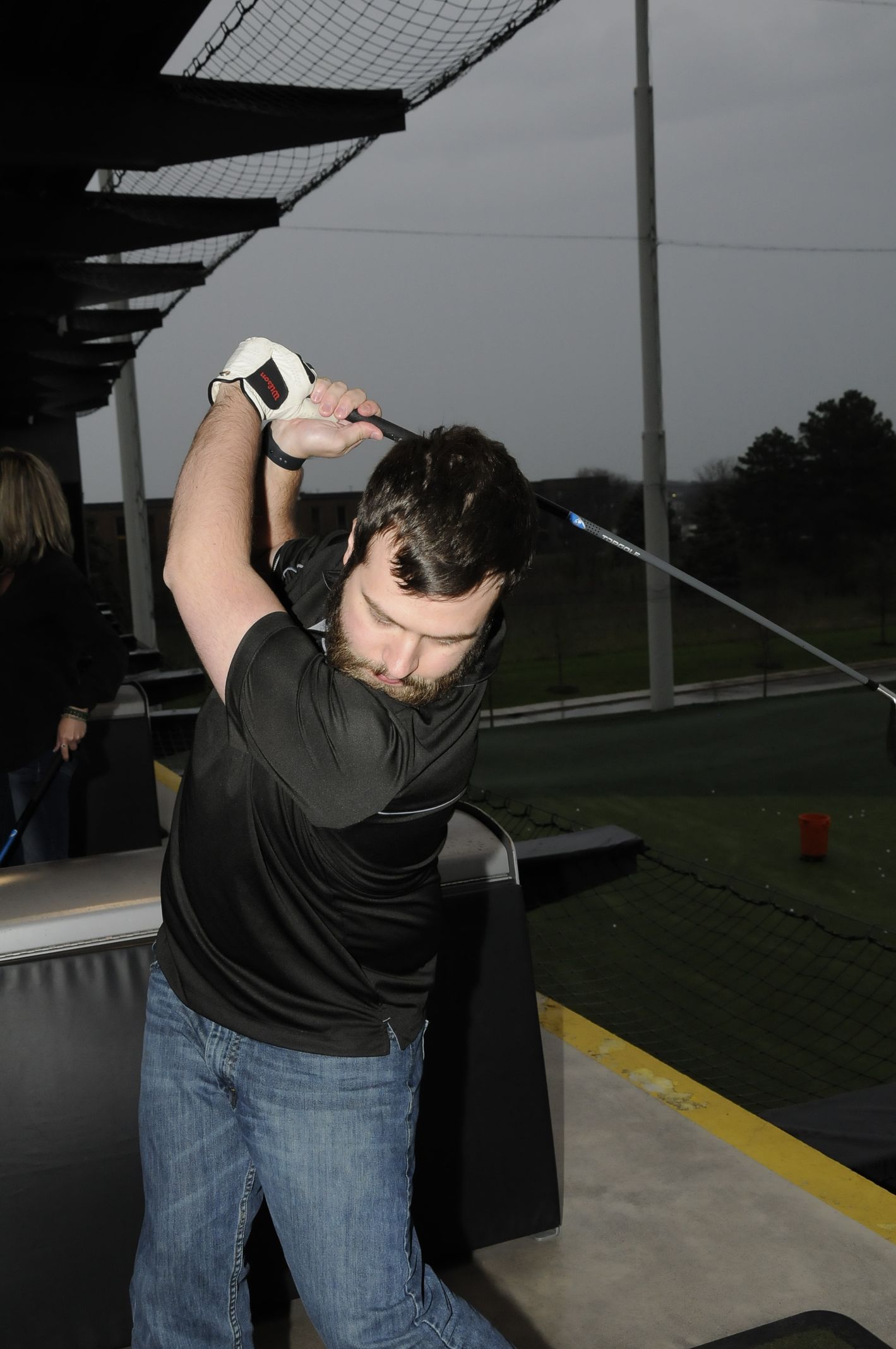A man in a black shirt is swinging a golf club