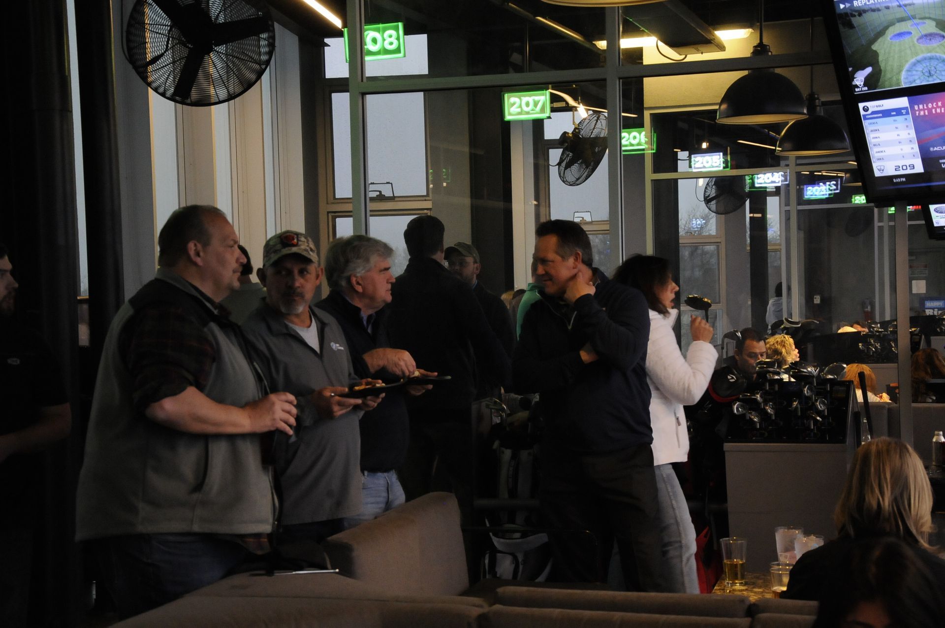 A group of people are standing in a restaurant talking to each other.