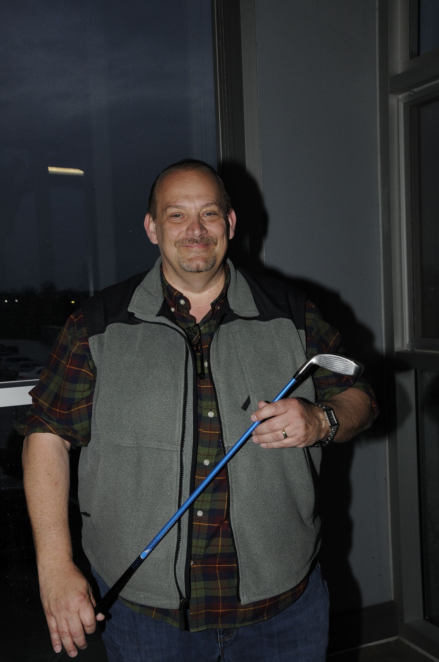 A man in a vest is holding a golf club.