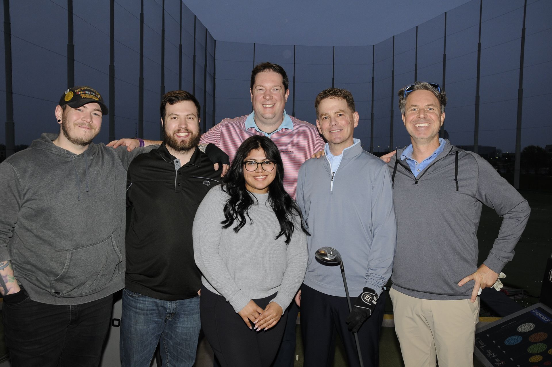 A group of people standing next to each other holding golf clubs.