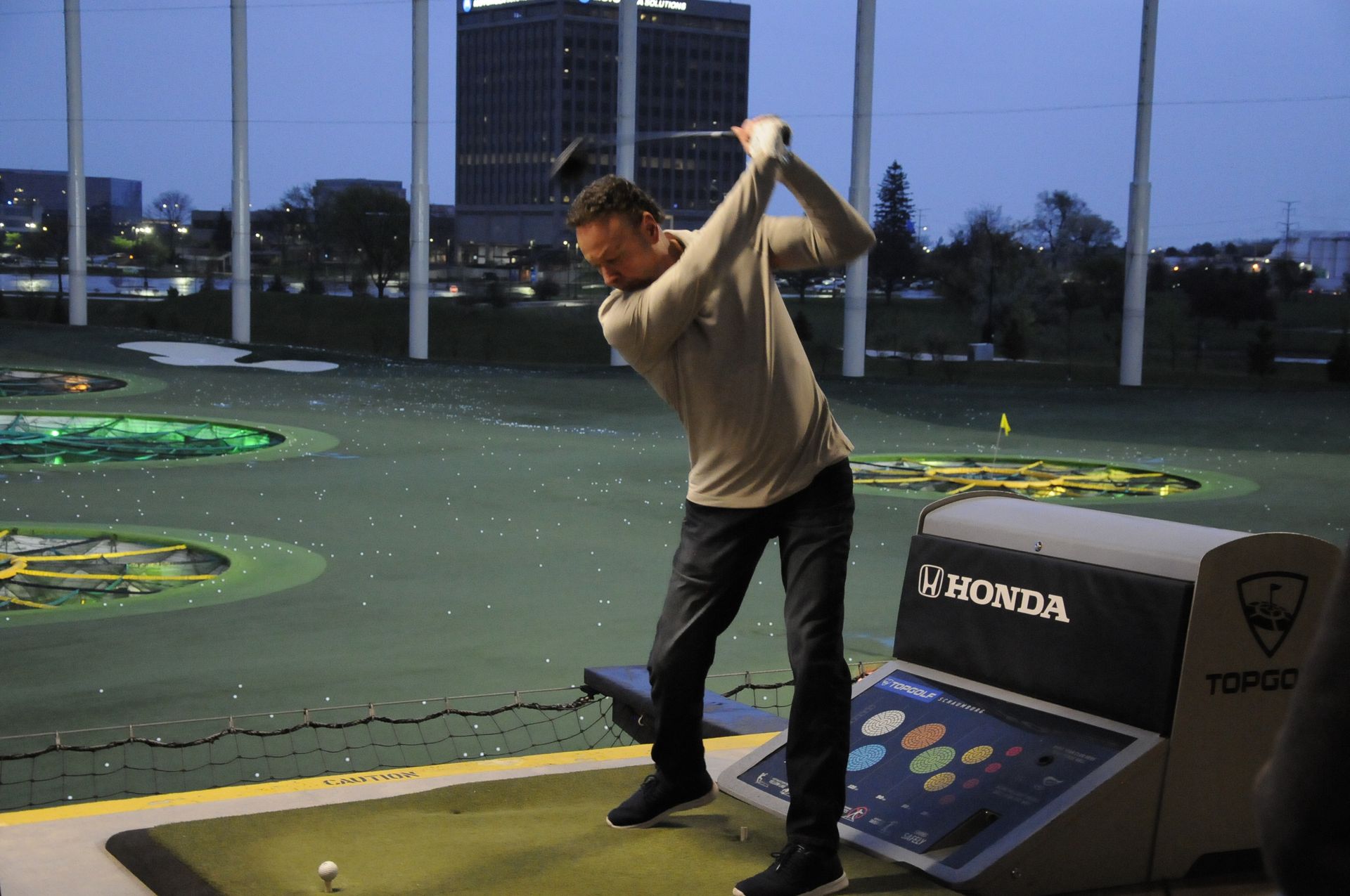 A man is swinging a golf club at a rounda machine