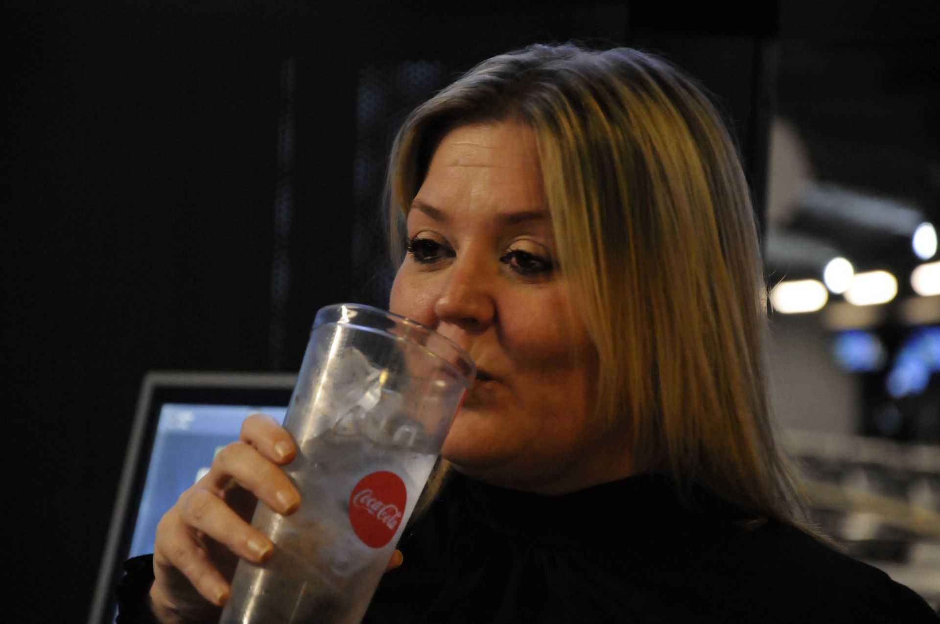 A woman is drinking from a coca cola glass