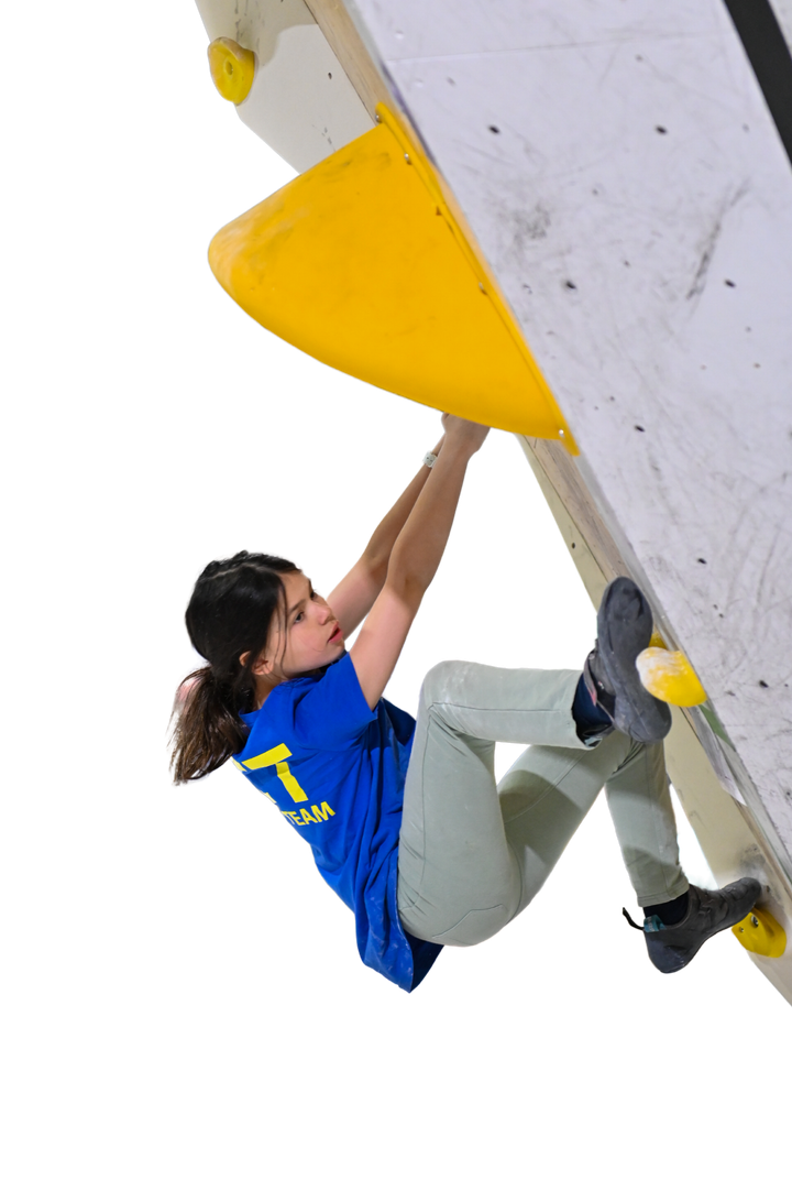 Rock climber in blue shirt clinging to yellow hold on white climbing wall.
