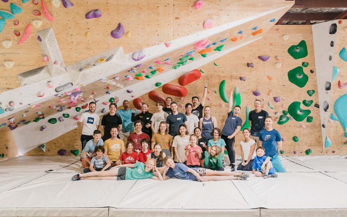 Group of people in a climbing gym posing in front of colorful climbing walls with holds.
