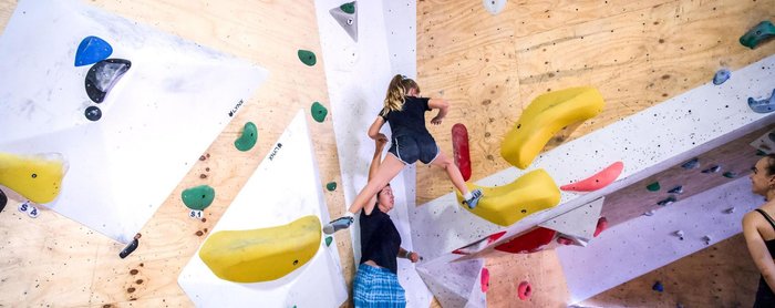 Indoor rock climber reaching for colorful holds on a bouldering wall