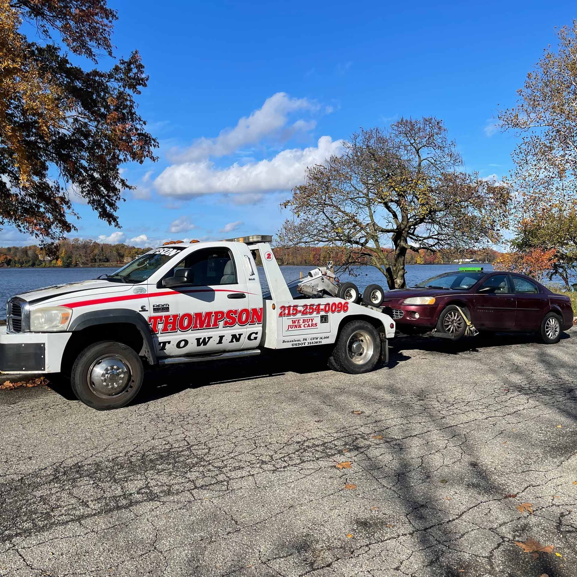 A picture of a car being towed by a Thompson Cash towing truck.
