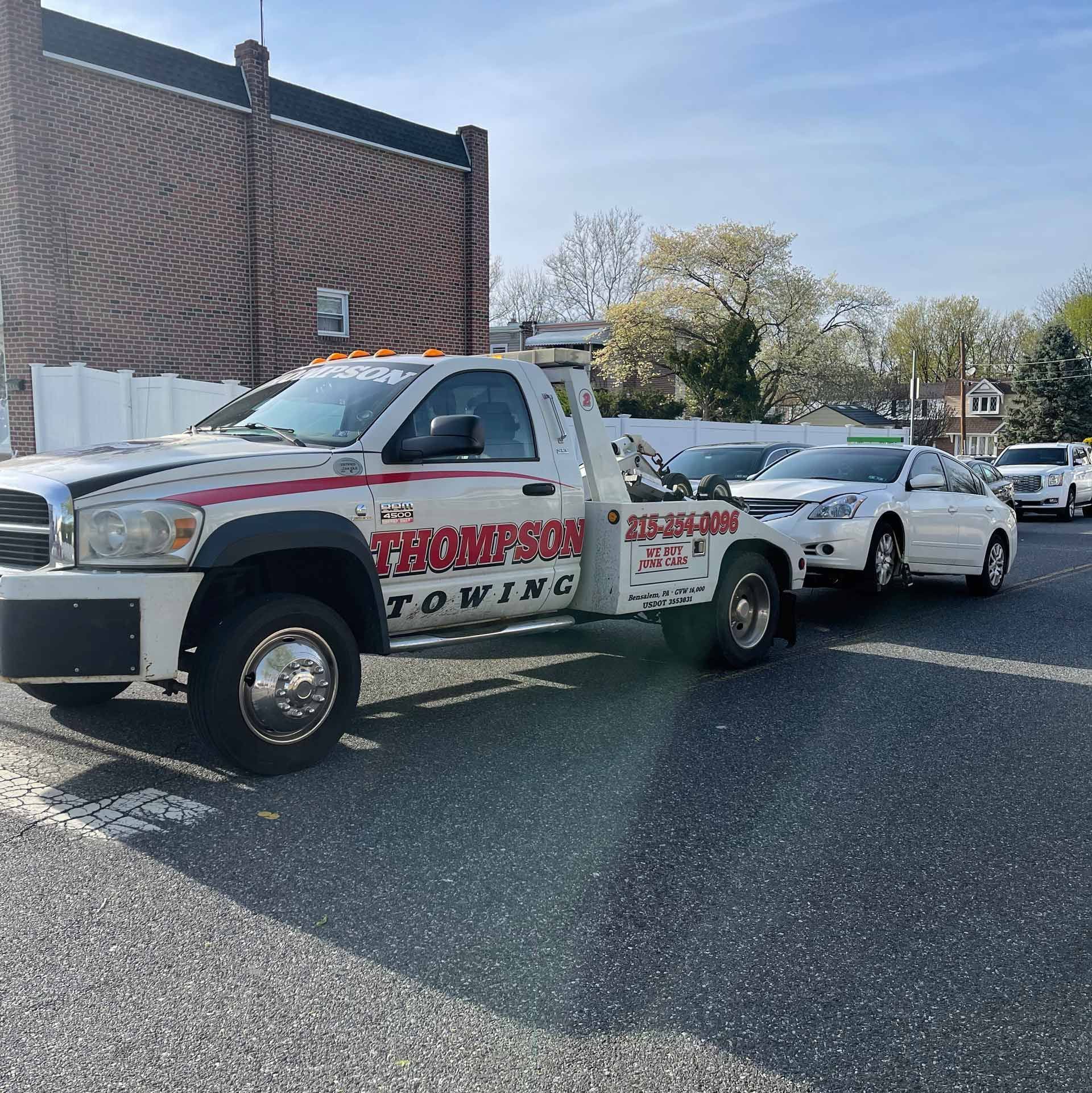 Tow truck towing a white car in Newportville, Pennsylvania.