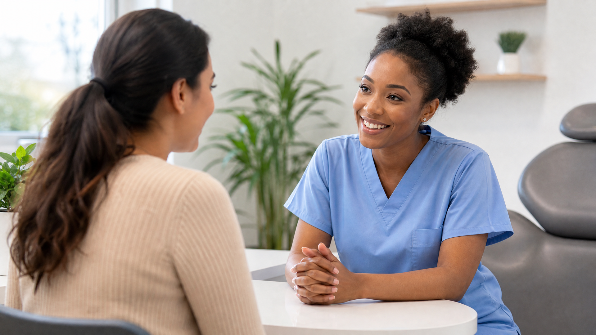 Nurse speaking with a seated patient in a bright clinic waiting area