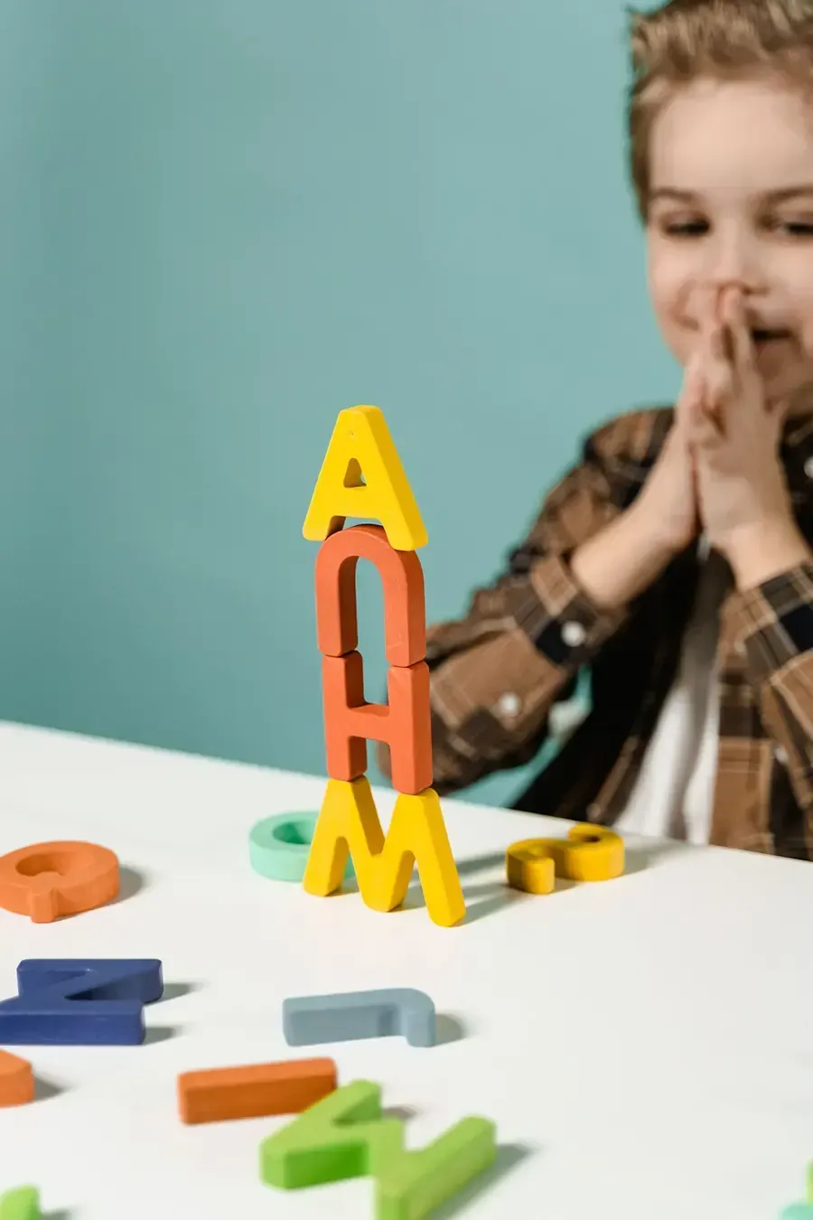 Child watching colorful magnetic letters on a white table