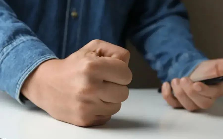 Clenched fist on a table beside another hand, suggesting frustration or emphasis