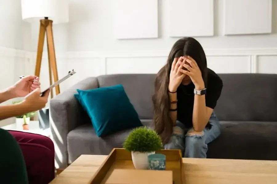 A woman holding her head while talking to a therapist
