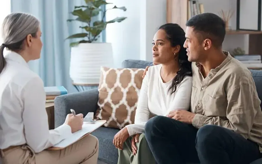 Therapist talking with a couple on a couch in a bright living room