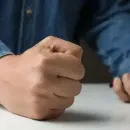 Clenched fist on a table beside another hand, suggesting frustration or emphasis