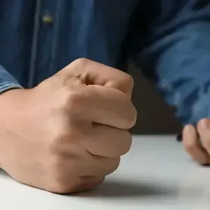 Clenched fist on a table beside another hand, suggesting frustration or emphasis
