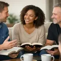 Three people smiling and discussing open books on a couch in a bright living room