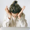 Person sitting at a desk with head in hands, appearing stressed or overwhelmed