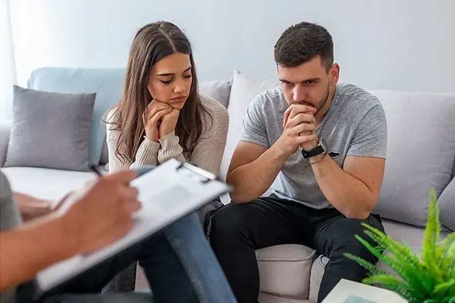 A couple sitting on a couch having premarital-counseling