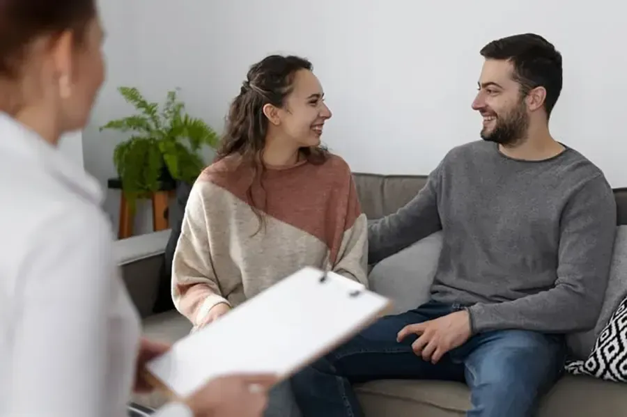 A smiling & sitting couple while having a session with a counselor