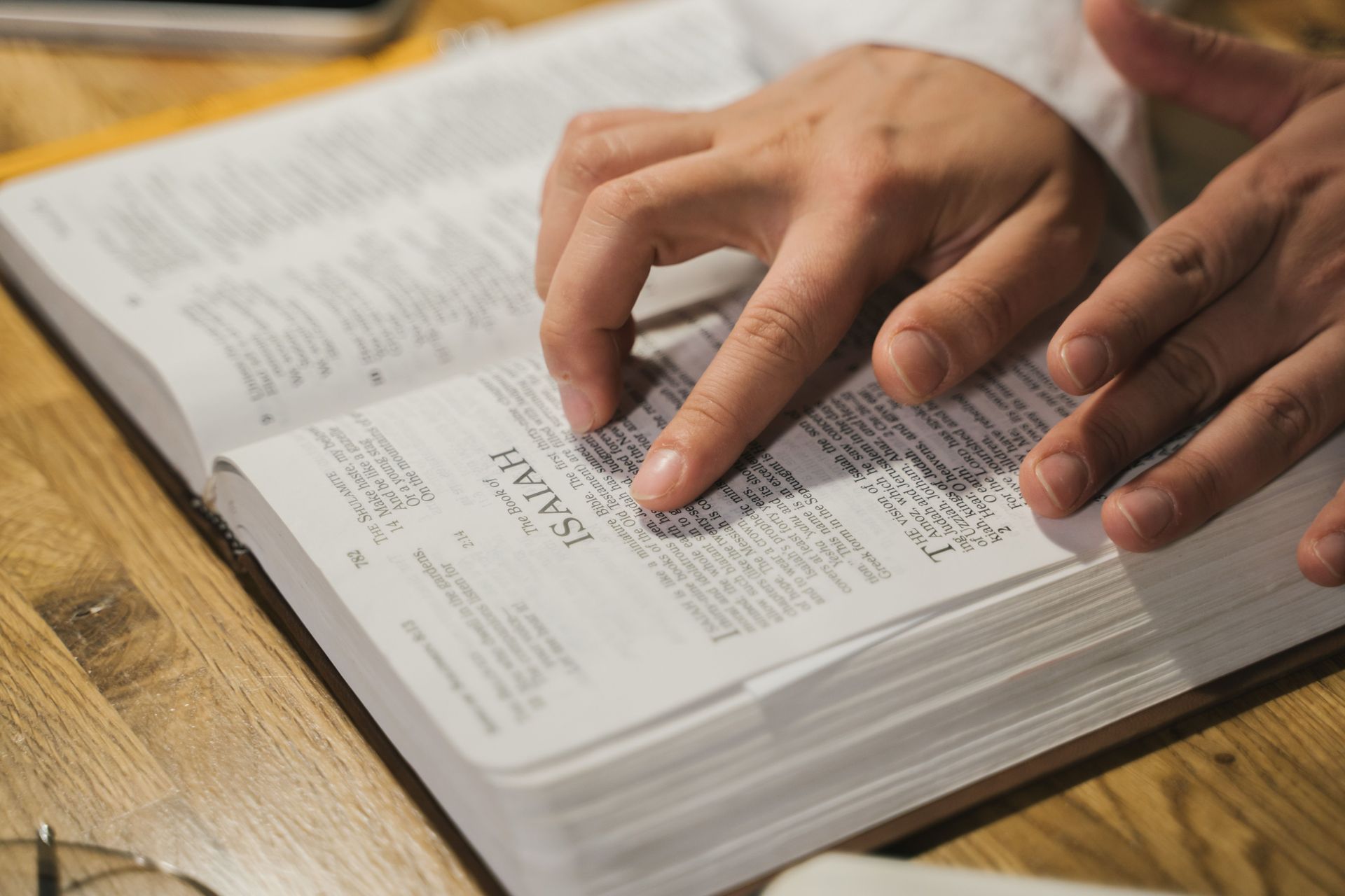 Hands tracing text in an open book on a wooden table