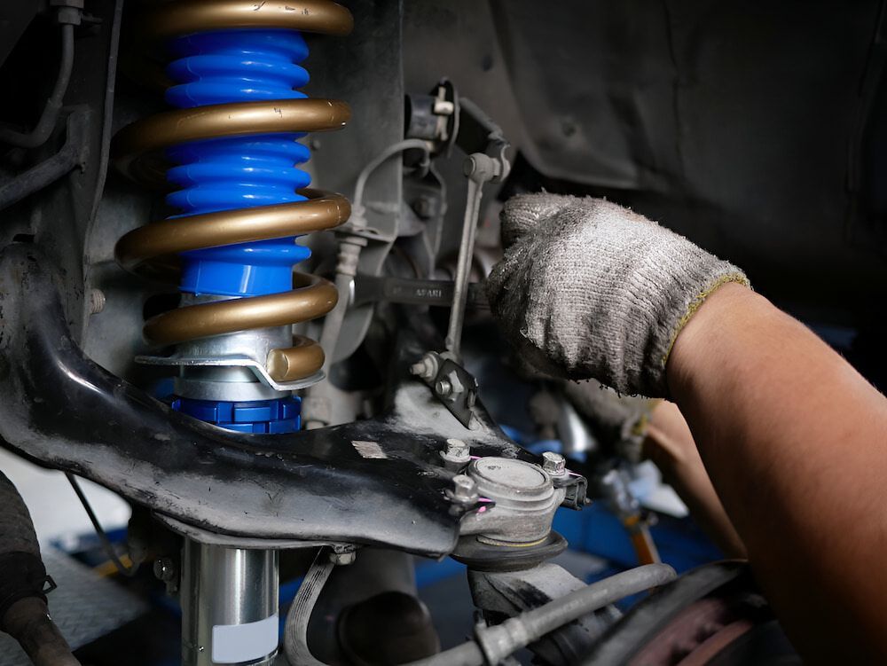 Mechanic Working on Car Suspension, Wearing Gloves — Scott Stanford Automotive in Nowra, NSW