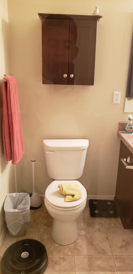 Small bathroom with a toilet, towel rack, wall cabinet, sink, and trash can.