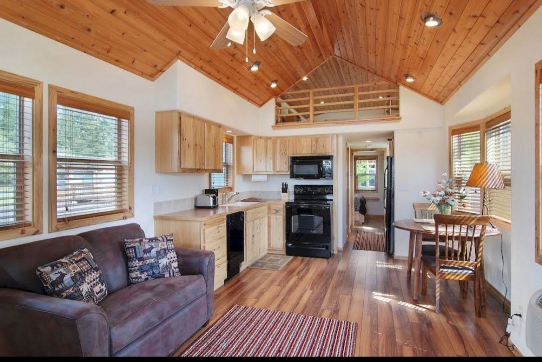 Cozy loft cabin interior with kitchen, sofa, wood ceiling, and dining nook under skylights