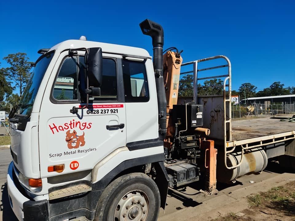 A White Truck With a Crane on the Back is Parked on the Side of the Road — Hastings Scrap Metal Recyclers in Wauchope, NSW