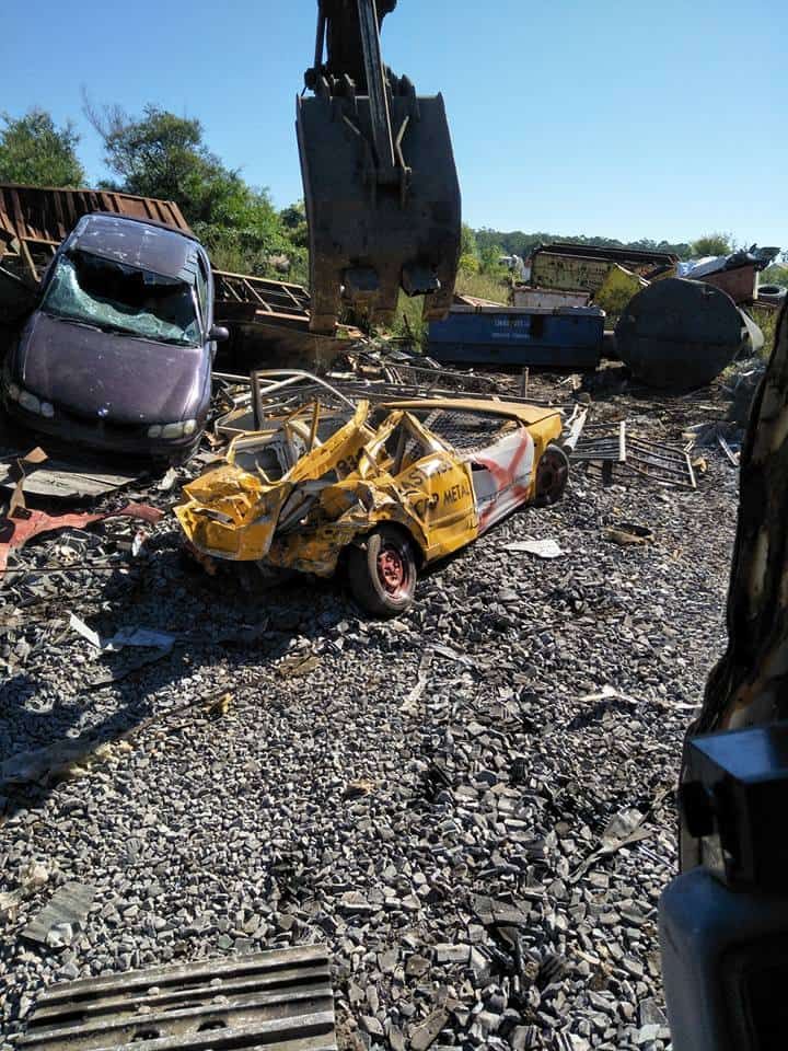 A Yellow Car is Sitting in the Middle of a Pile of Junk — Hastings Scrap Metal Recyclers in Wauchope, NSW