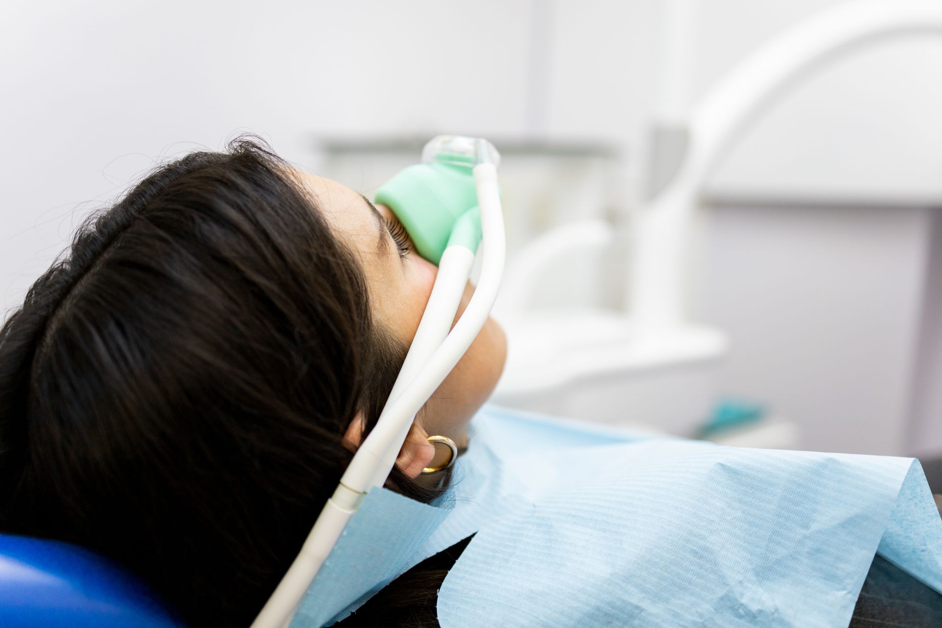 A woman is laying in a dental chair with an oxygen mask on her face.