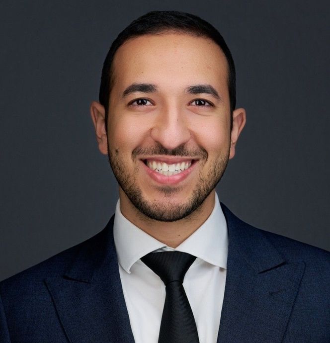 A man in a suit and tie is smiling for the camera