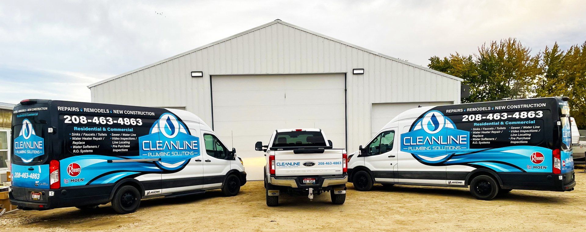 Three vans and a truck parked in front of a white building with the company name 