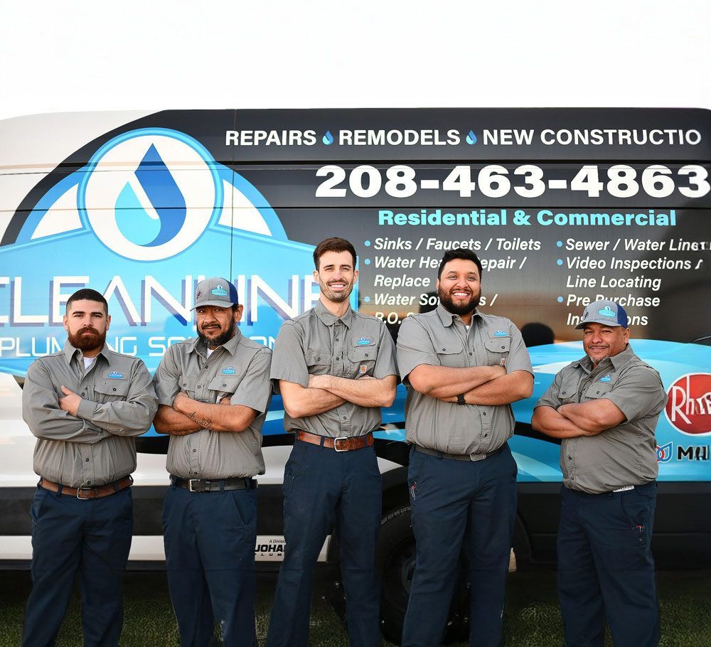 Five plumbing professionals in grey shirts stand arms crossed in front of their company van.