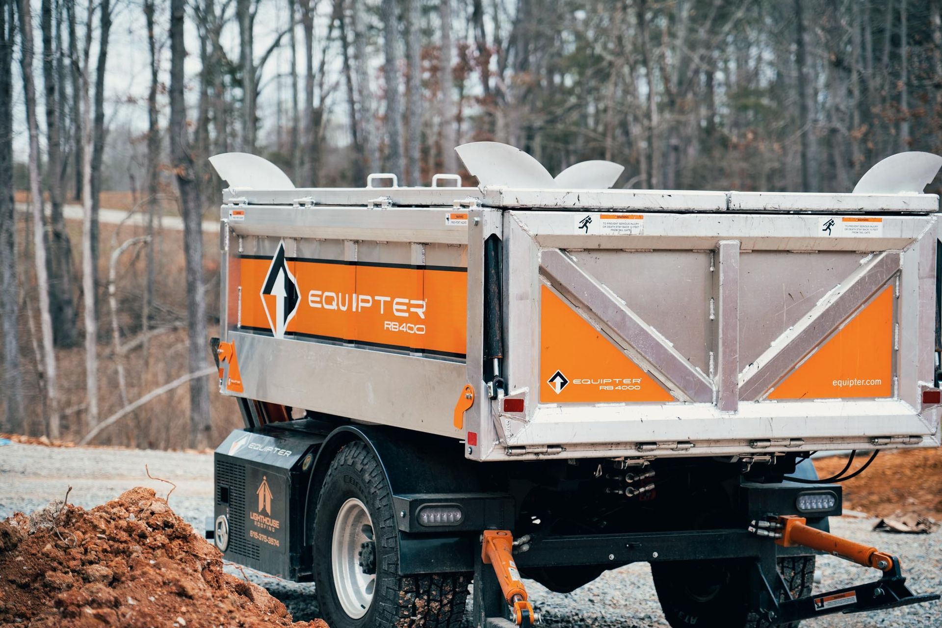 A dump truck is parked on the side of the road next to a pile of dirt.