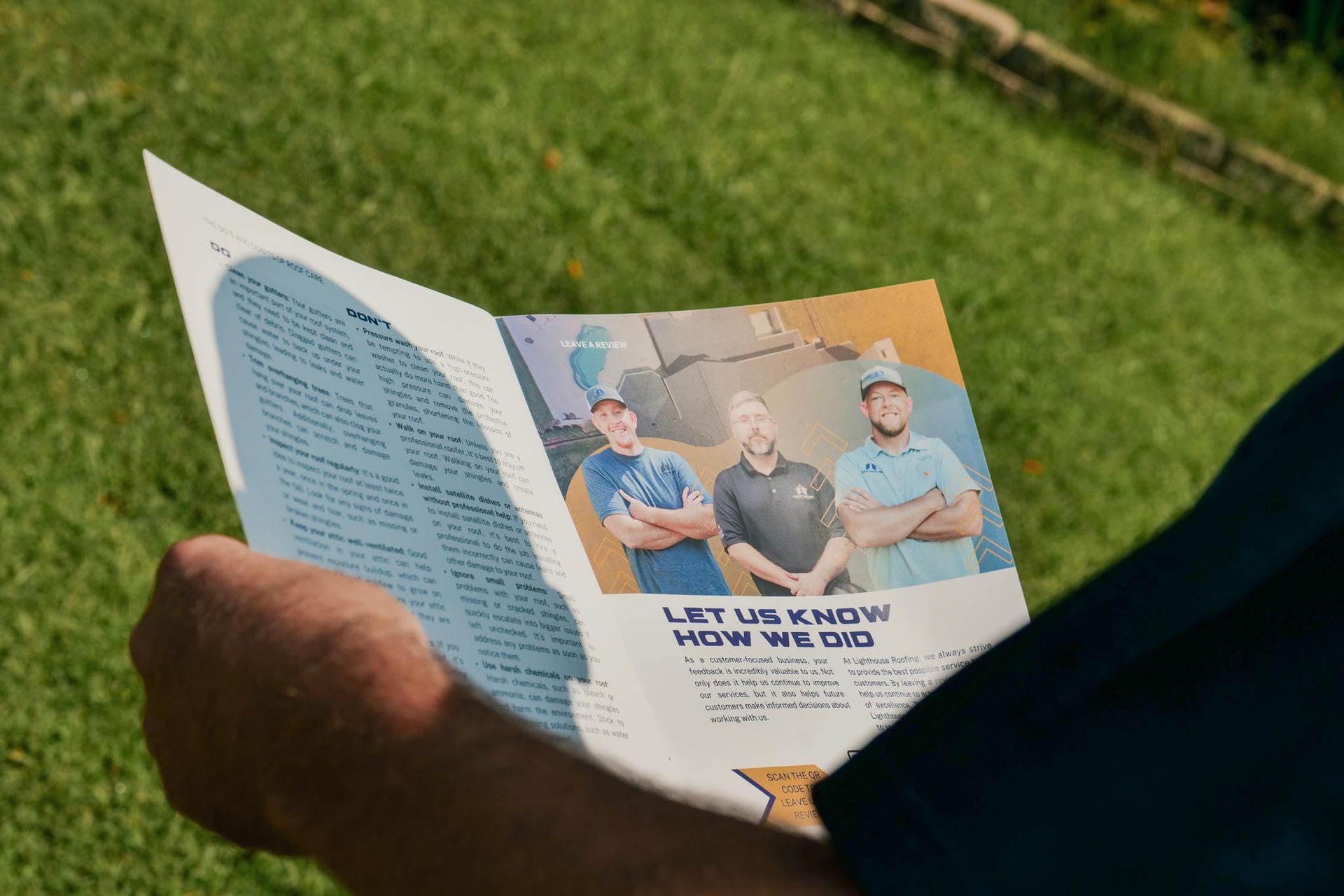 A person is holding a brochure with a picture of three men on it.