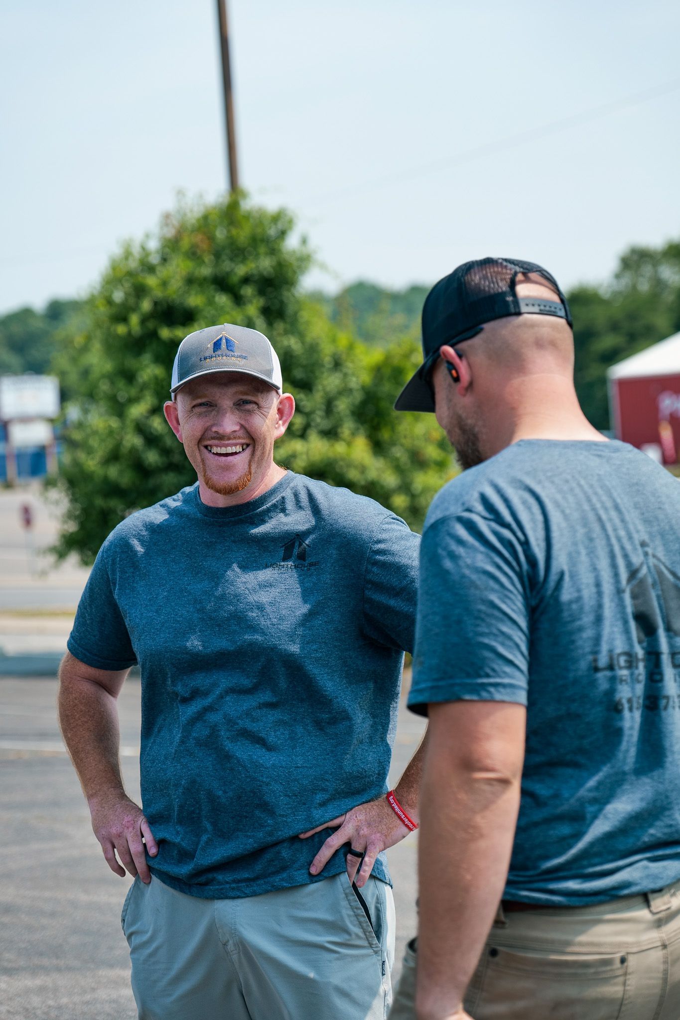 Two men are standing next to each other in a parking lot and talking.