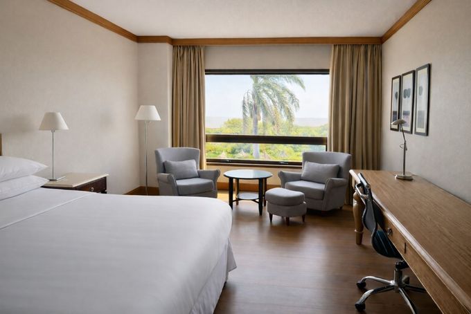 Habitación bien decorada con cama de madera, lámparas de noche, cómoda, espejo y luz cálida en el techo.