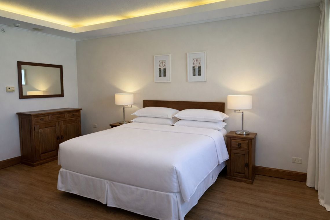 Habitación bien decorada con cama de madera, lámparas de noche, cómoda, espejo y luz cálida en el techo.
