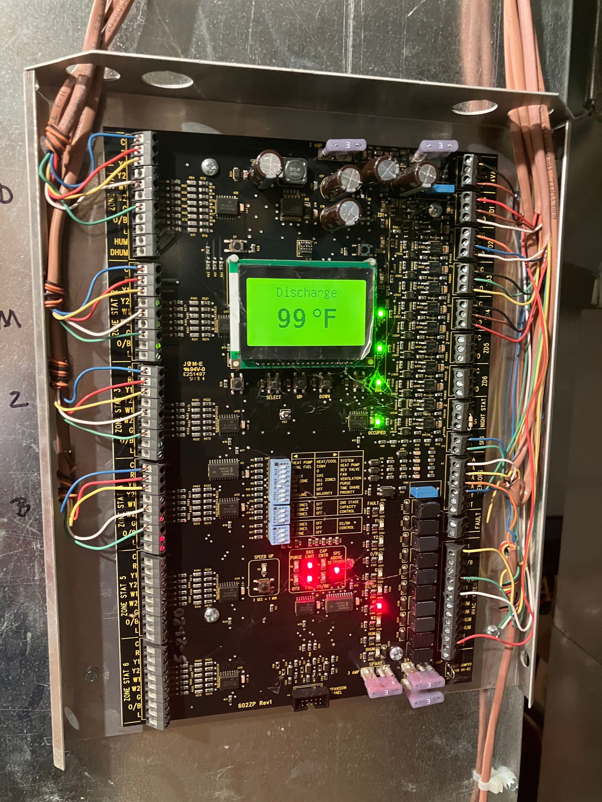 Circuit board with a screen displaying 99°F, surrounded by wires and lights.
