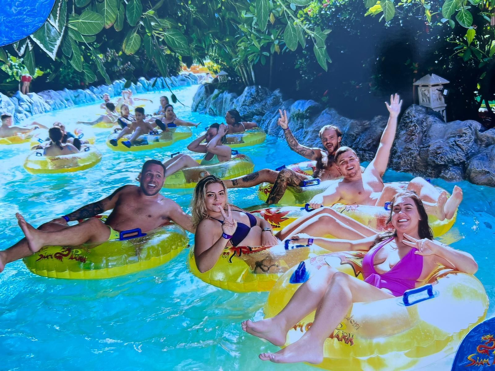 People relaxing on inflatable tubes in a tropical pool with turquoise water and lush greenery