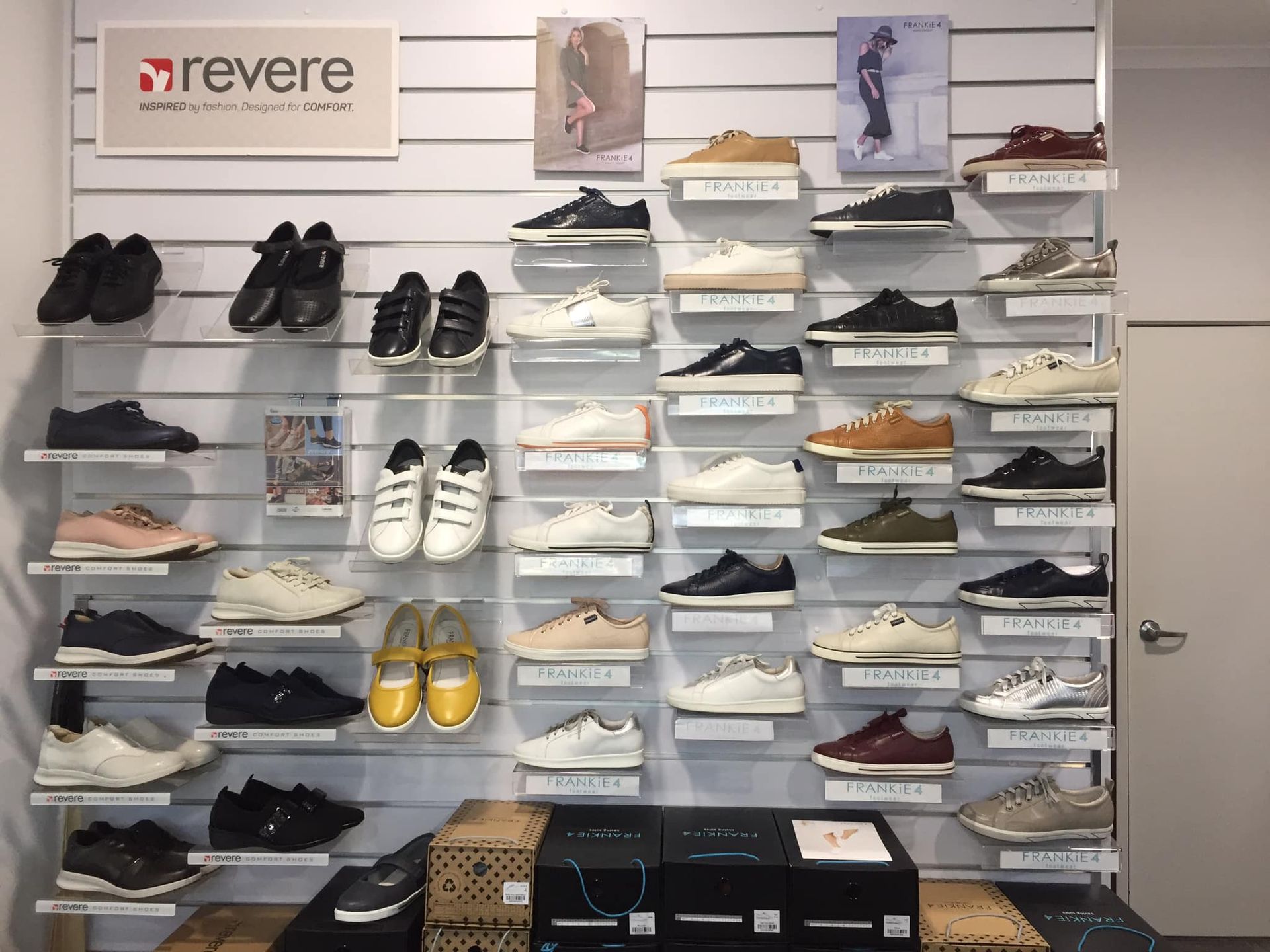 Shoe Store Display Wall With Rows of Sneakers and Boots on White Shelves — Lord Street Podiatry in Port Macquarie, NSW