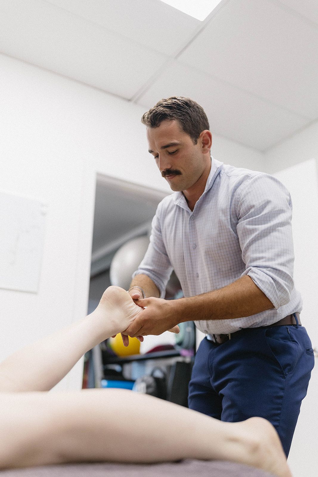 Therapist Stretching a Patient’s Leg in A Bright Clinic Room — Lord Street Podiatry in Port Macquarie, NSW